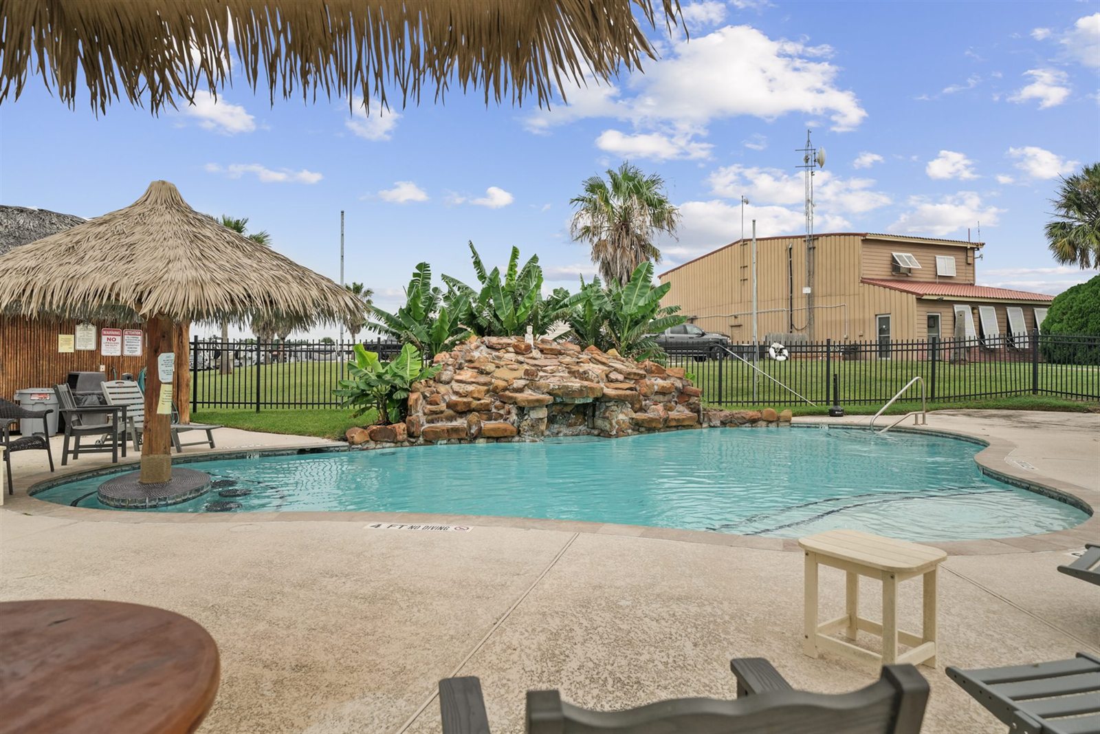 Resort Pool Rock Waterfall & Thatched Palapa Shaded Loungers